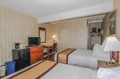 a hotel room with two beds and a desk at Canadas Best Value Inn Chinook Station in Calgary