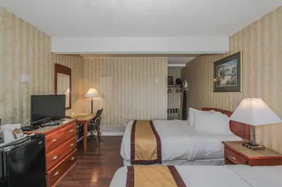 a hotel room with two beds and a television at Canadas Best Value Inn Chinook Station in Calgary