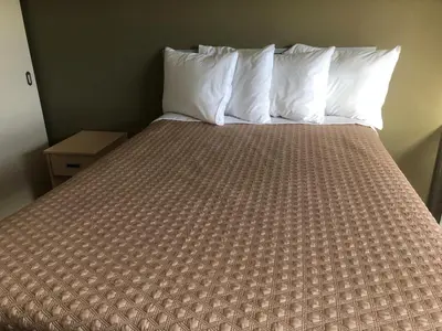 a bed with white pillows and a brown comforter at SAIT Residence & Conference Centre - Calgary in Calgary