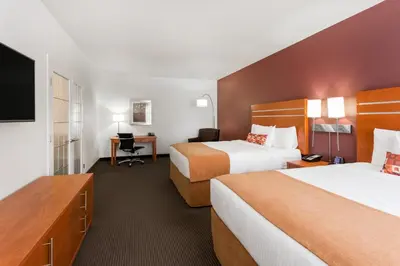 a hotel room with two beds and a desk at Wingate by Wyndham Calgary South in Calgary