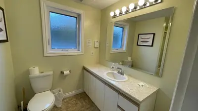 a bathroom with a toilet and a sink and a mirror at Buena Vista by the Sea in Qualicum Beach