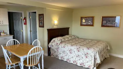a bedroom with a bed and a table with chairs at Buena Vista by the Sea in Qualicum Beach