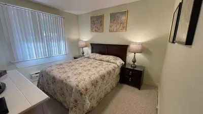 a bedroom with a bed and two lamps and a window at Buena Vista by the Sea in Qualicum Beach