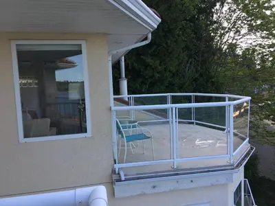 a balcony with a blue chair on a house at Casa Grande Inn in Qualicum Beach