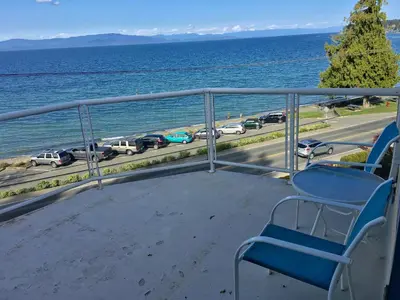 a blue chair sitting on a balcony overlooking the ocean at Casa Grande Inn in Qualicum Beach