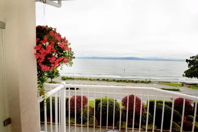 a balcony with a view of the ocean at Casa Grande Inn in Qualicum Beach