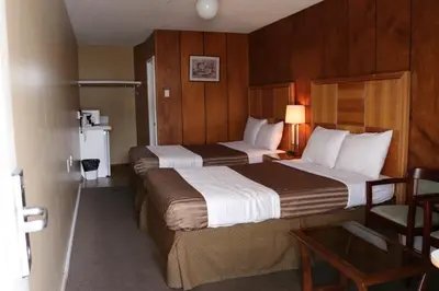 a hotel room with two beds and a table at Plaza Motel in Penticton