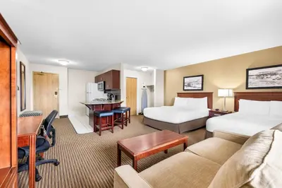 a hotel room with two beds and a couch at SureStay Plus Hotel by Best Western Drumheller in Drumheller