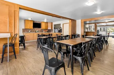 a restaurant with tables and chairs and a kitchen at SureStay Plus Hotel by Best Western Drumheller in Drumheller
