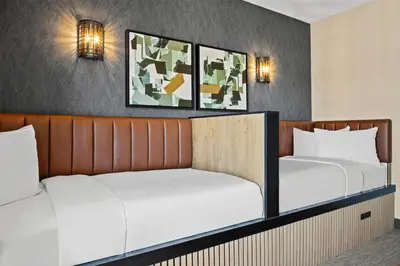 two beds in a hotel room with two lamps at Ramada by Wyndham Drumheller Hotel & Suites in Drumheller