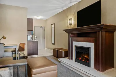 a living room with a fireplace with a flat screen tv at Ramada by Wyndham Drumheller Hotel & Suites in Drumheller