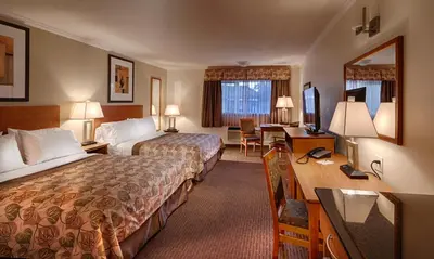 a hotel room with two beds and a desk at Canalta Jurassic - Drumheller in Drumheller