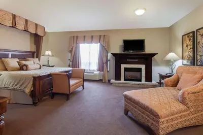 a hotel room with a bed and a fireplace at Ramada by Wyndham Camrose in Camrose
