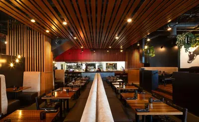 a dining room with wooden tables and a kitchen at Hotel Le Germain Calgary in Calgary