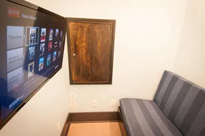 a room with a couch and a tv and a wall at Ocean Island Inn | Backpackers | Suites in Victoria