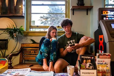 a man and a woman sitting on a table at Ocean Island Inn | Backpackers | Suites in Victoria