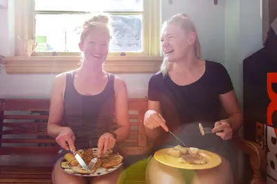 two women sitting down with plates of food at Ocean Island Inn | Backpackers | Suites in Victoria