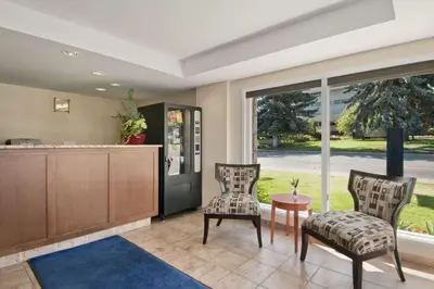 a lobby with two chairs and a counter and a table at Travelodge by Wyndham Kamloops in Kamloops