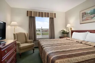 a hotel room with a bed and a chair and a window at Travelodge by Wyndham Stony Plain in Stony Plain