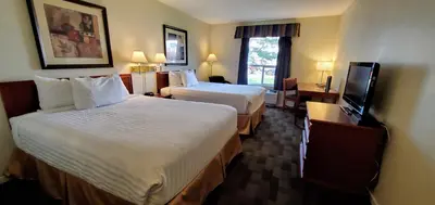 a hotel room with two beds and a flat screen tv at Travelodge by Wyndham Stony Plain in Stony Plain