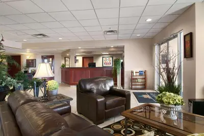 a living room with a leather couch and a table at Travelodge by Wyndham Stony Plain in Stony Plain