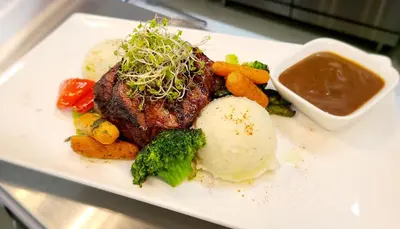 a plate of food with meat and vegetables and sauce at Executive House Suites Hotel & Conference Centre in High Level