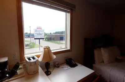 a bedroom with a desk with a lamp and a window at Executive House Suites Hotel & Conference Centre in High Level