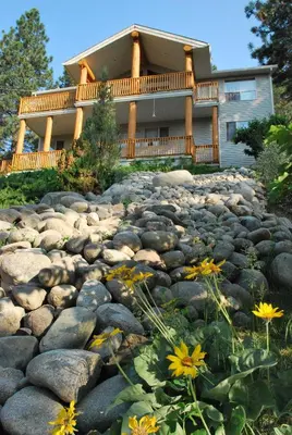 a house with a large yard with rocks and flowers at PineWood Guesthouse in Peachland