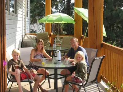 a family sitting at a table on a patio at PineWood Guesthouse in Peachland