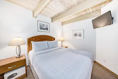 a white bedroom with a bed and a television at Jasper Inn & Suites by INNhotels in Jasper