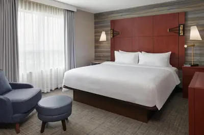a hotel room with a large bed and a chair at Residence Inn by Marriott Calgary Airport in Calgary