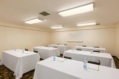 a room with white tables and chairs and a whiteboard at High Prairie Inn in High Prairie
