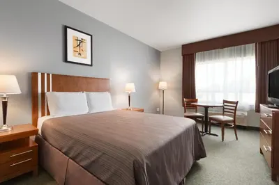 a hotel room with a large bed and a table at High Prairie Inn in High Prairie