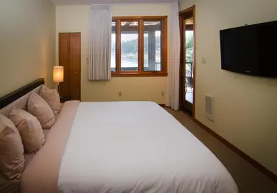 a bedroom with a large white bed and a flat screen tv at Galiano Oceanfront Inn & Spa in Galiano