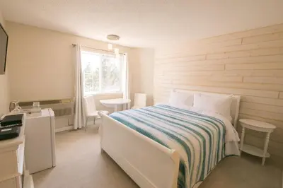 a white bedroom with a bed and a window at Inn on Canyon in Radium Hot Springs