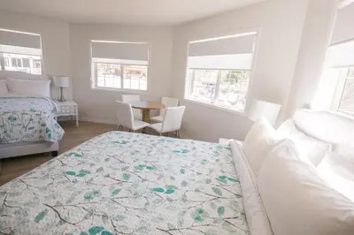 a bedroom with a bed and a table and windows at Inn on Canyon in Radium Hot Springs