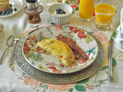 a plate of breakfast food with eggs bacon and orange juice at Eagle Rock Bed and Breakfast in Chemainus