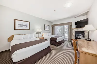 a hotel room with two beds and a fireplace at Canmore Rocky Mountain Inn in Canmore