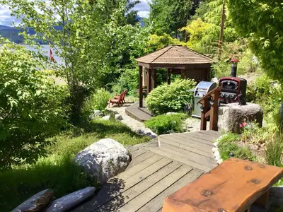 a wooden boardwalk with a gazebo in a garden at The Tuwanek Bed and Breakfast in Sechelt
