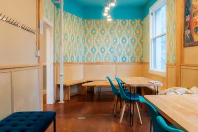 a dining room with wooden tables and blue chairs at The Cambie Hostel Seymour in Vancouver