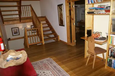 a living room with wooden floors and a spiral staircase at Alpenglow Bed and Breakfast in Kimberley