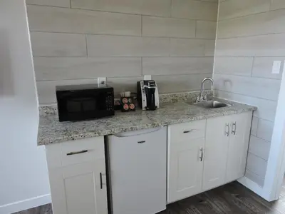 a kitchen counter with a microwave and a sink at Almo Court Motel in Cranbrook