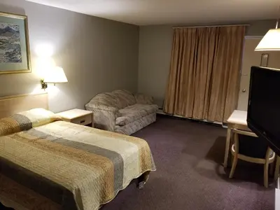 a hotel room with two beds and a desk at Slumber Lodge Williams Lake in Williams Lake
