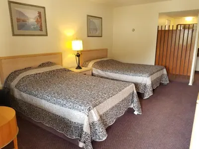 a hotel room with two beds and a table at Slumber Lodge Williams Lake in Williams Lake