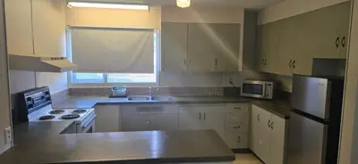 a kitchen with white cabinets and a sink and a refrigerator at Slumber Lodge Williams Lake in Williams Lake