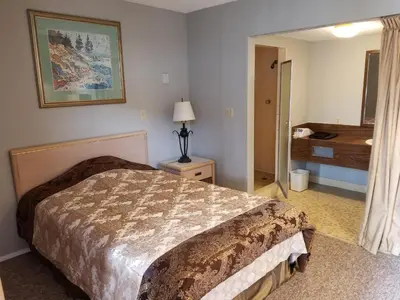 a hotel room with a bed and a bathroom at Slumber Lodge Williams Lake in Williams Lake