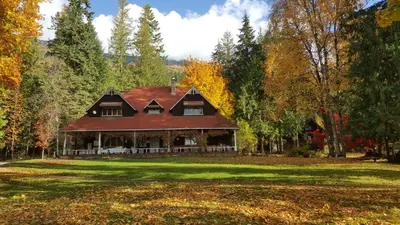 a large house with a red roof on a field at Wedgwood Manor and Glamping Retreat in Crawford Bay
