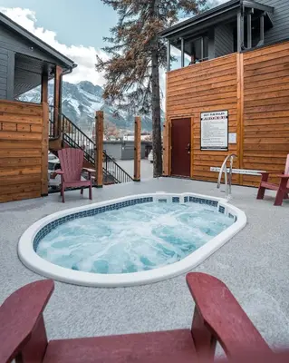 a hot tub on a patio with two chairs at Lamphouse By Basecamp in Canmore