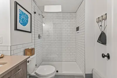 a white bathroom with a toilet and a shower at Lamphouse By Basecamp in Canmore
