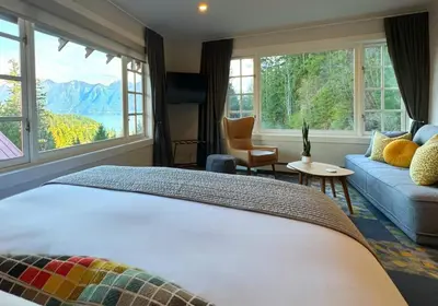 a bedroom with a bed and a couch and windows at Artisan Suites on Bowen in Bowen Island